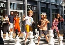 Groep mensen bij een groot schaakspel op een plein